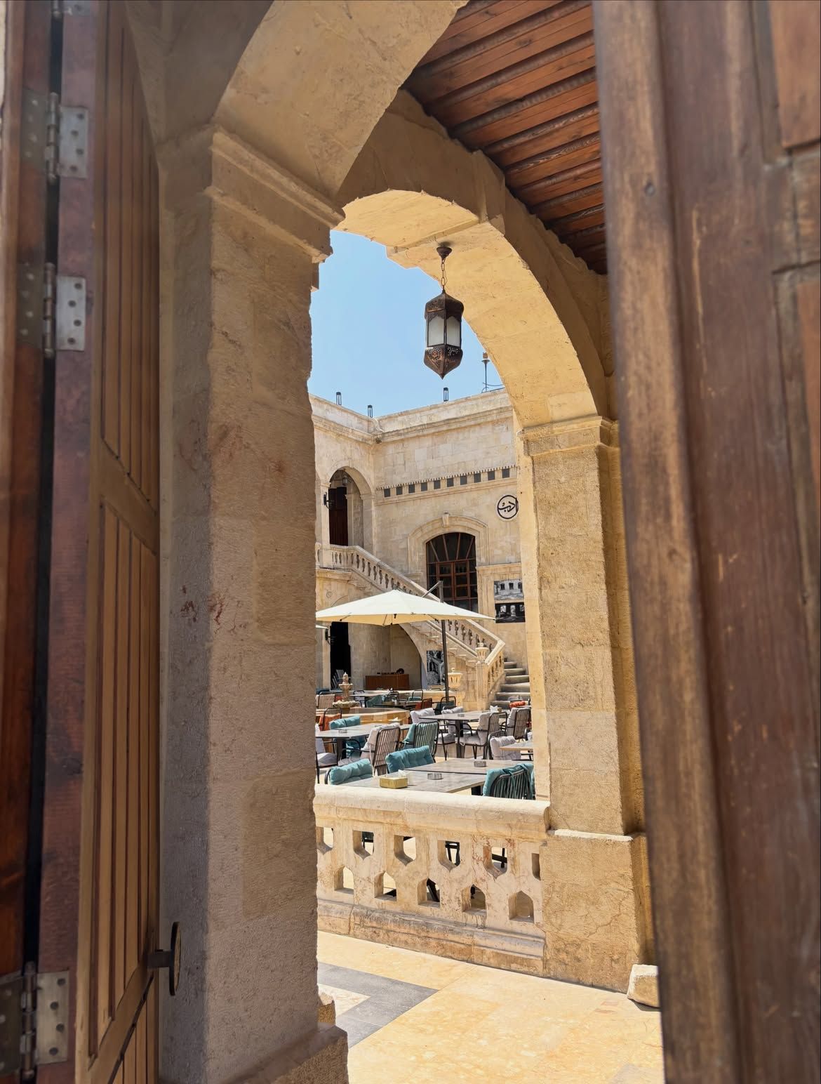Stone archway opening onto a courtyard café with a hanging lantern