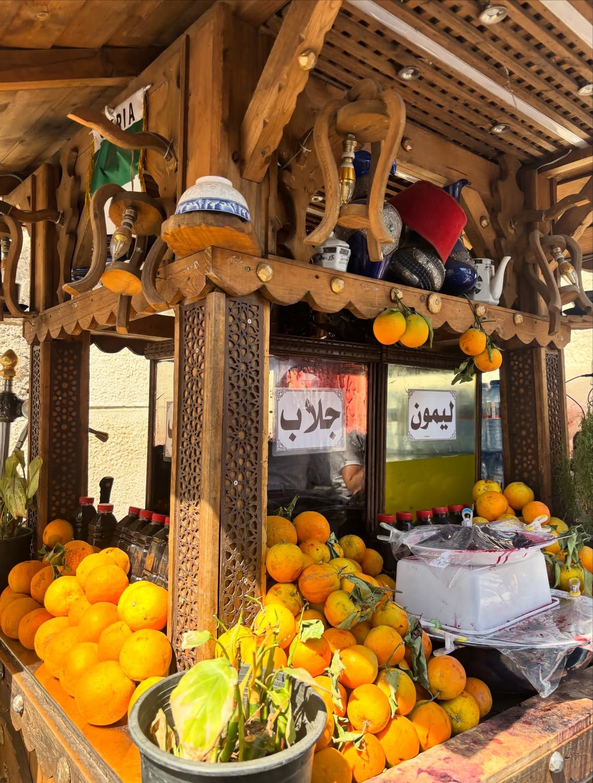 Wooden juice stand piled with oranges, with signs for jallab and lemon